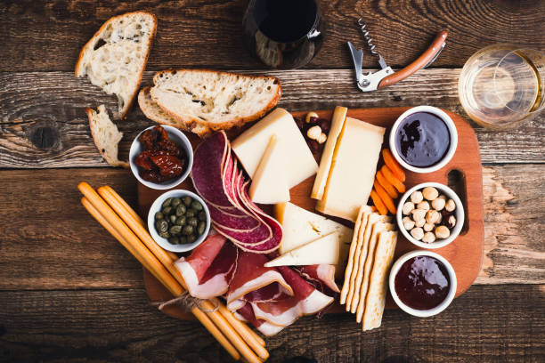 Plateau apéro vu de haut avec fromages, charcuterie, pain et verre de vin