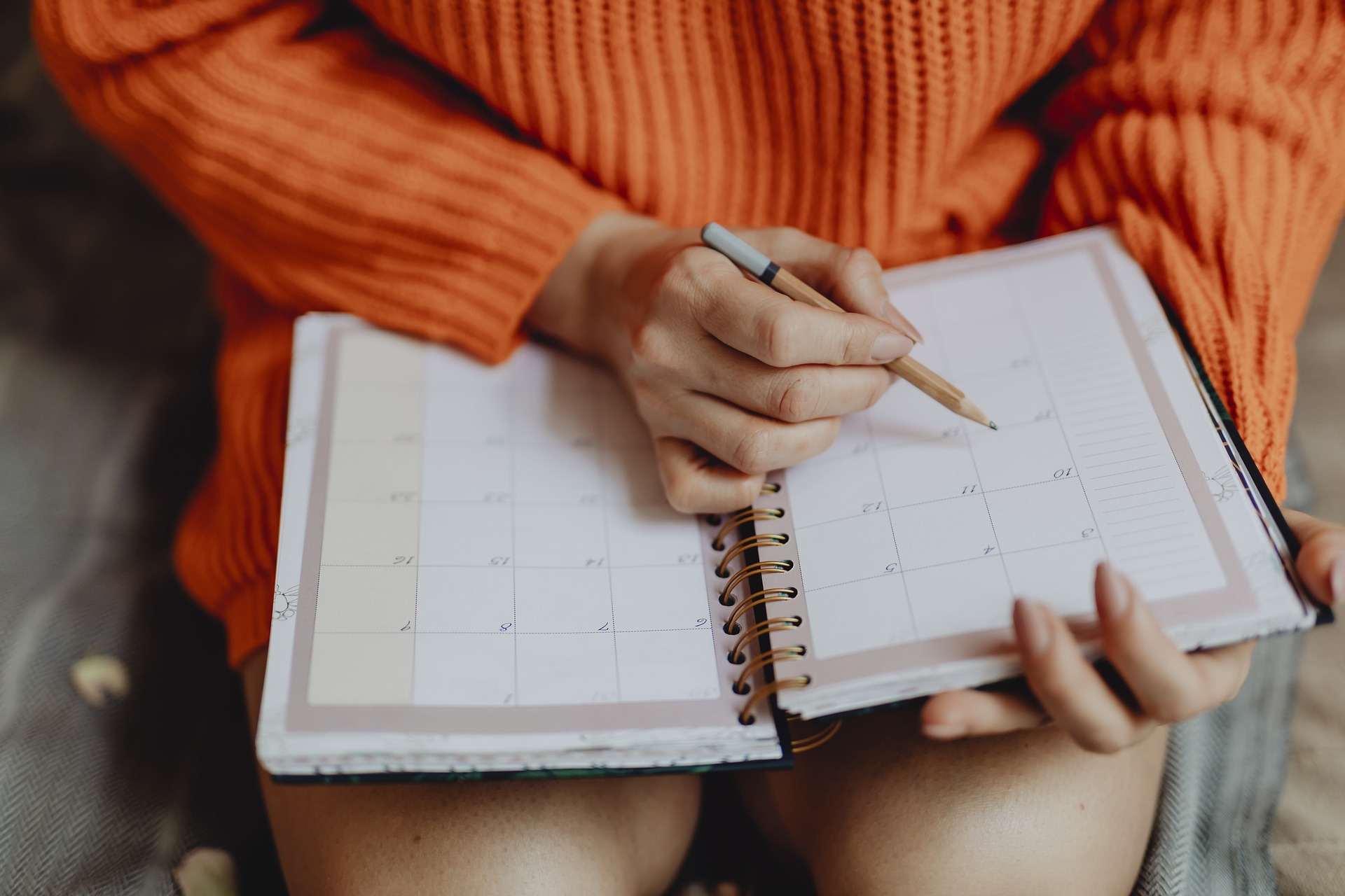 Femme assise avec un agenda sur les genoux et un crayon dans la main droite