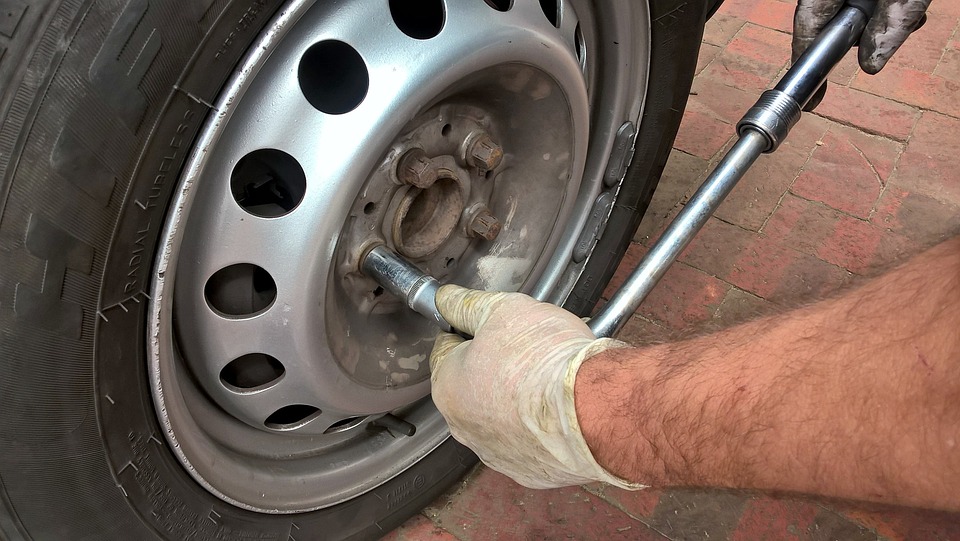 Homme en train de changer une roue sur sa voiture après un pneu crevé