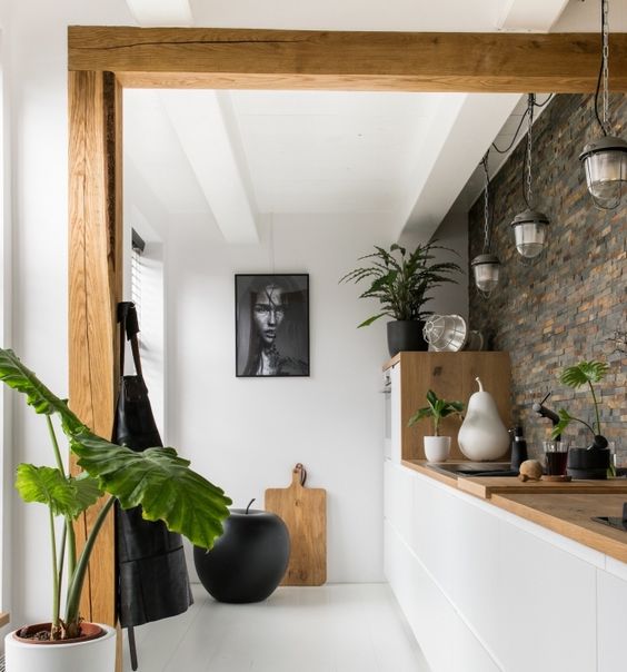 cuisine semi ouverte blanc et bois avec mur en pierre