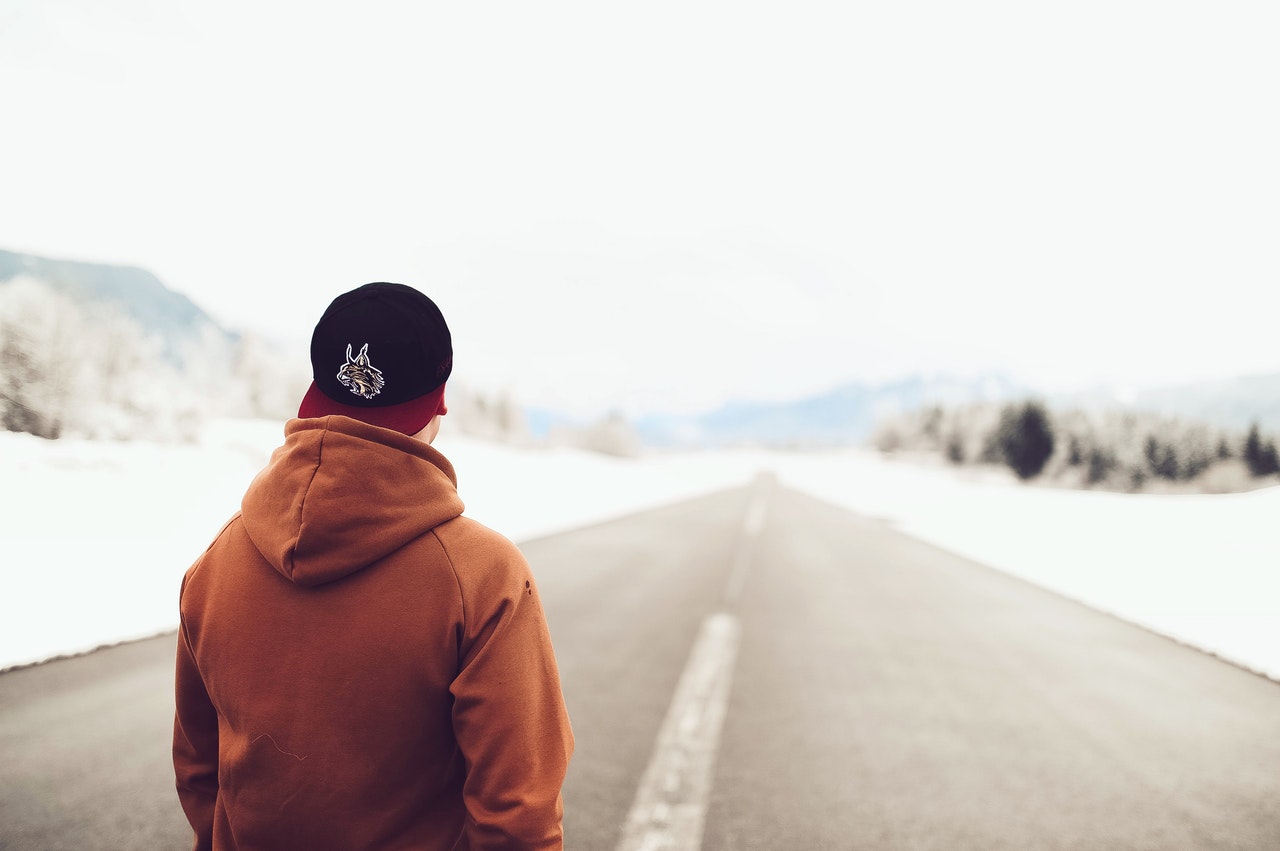 homme de dos sur une route enneigée